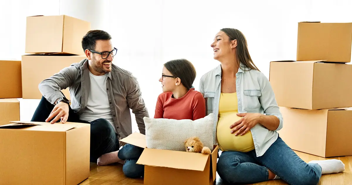 Family smiling and unpacking boxes together in a new home.