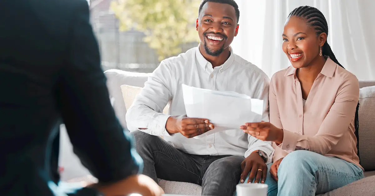 Happy couple reviewing documents with financial advisor, smiling and planning.