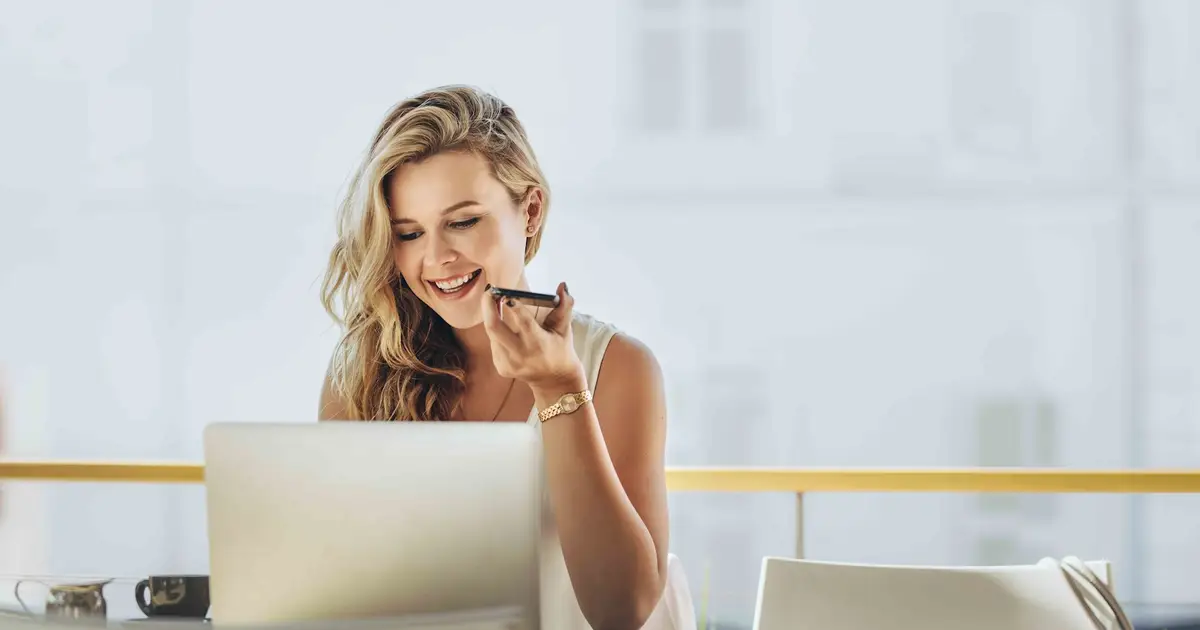 Smiling woman speaking on the phone while using laptop.