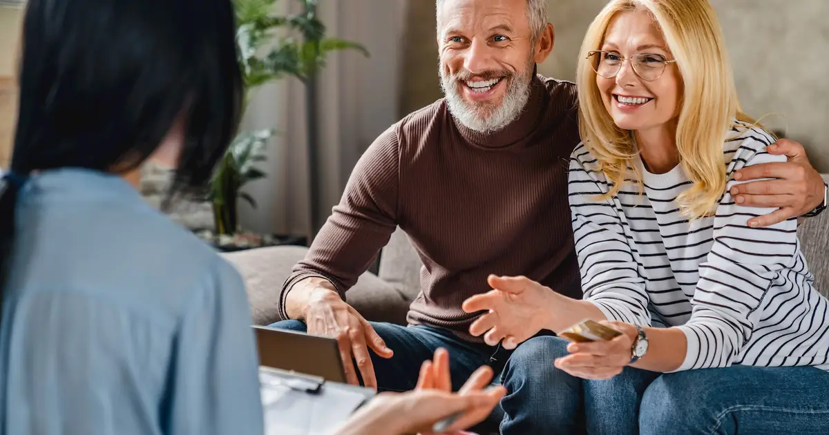 Senior couple discussing mortgage options with advisor, smiling and engaged.