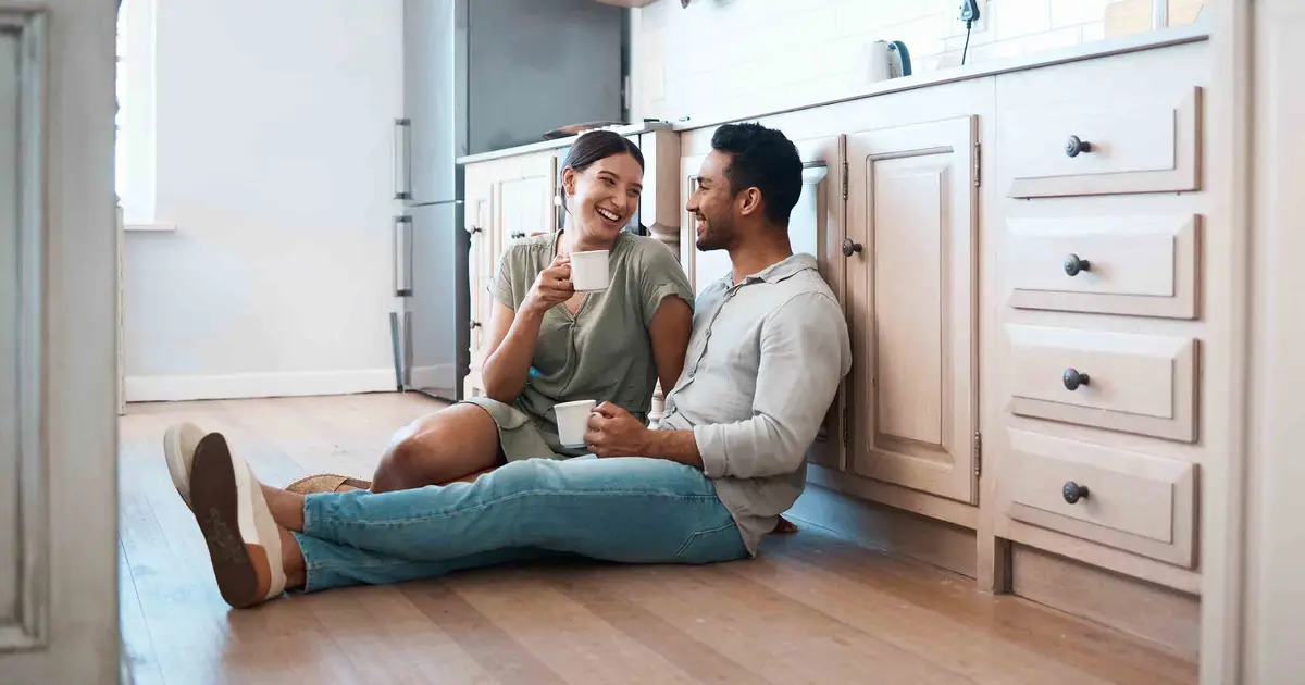 Couple drinking coffee together on the kitchen floor.