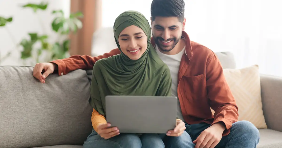 Smiling couple on couch with laptop.