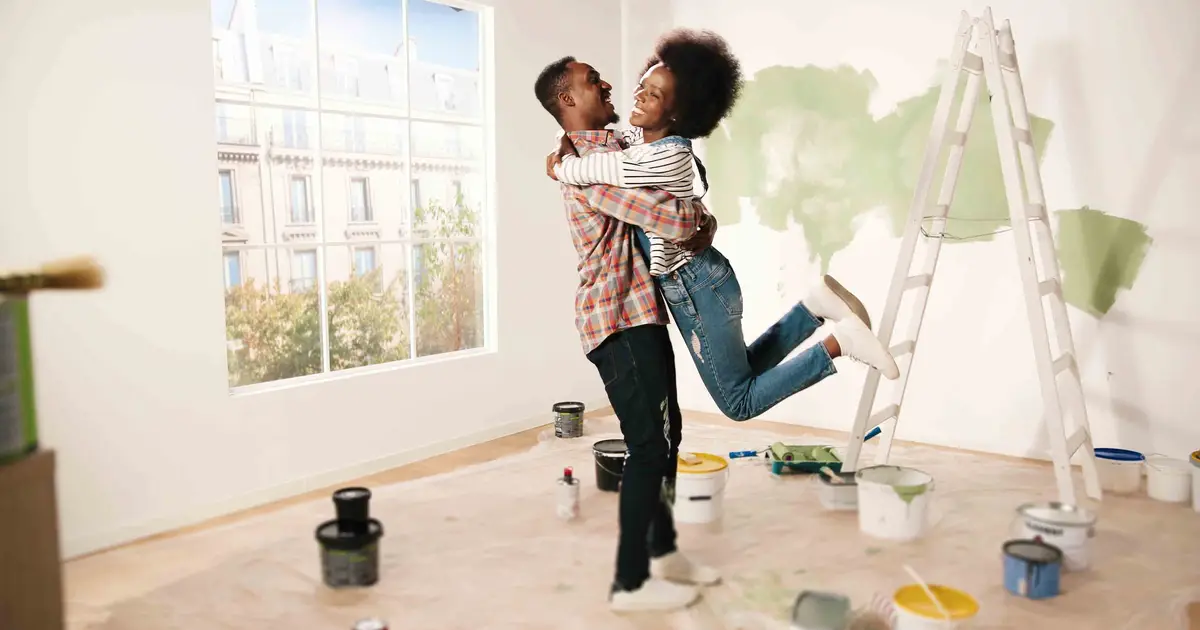 Couple embracing in a partially painted room.