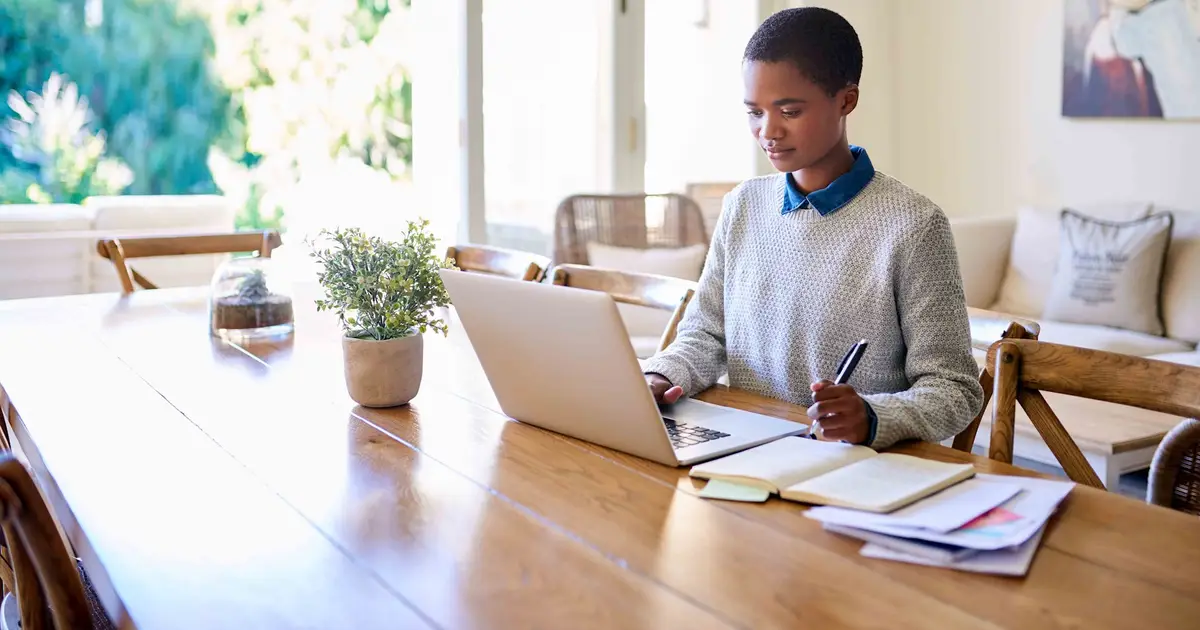Person working on laptop at dining table.
