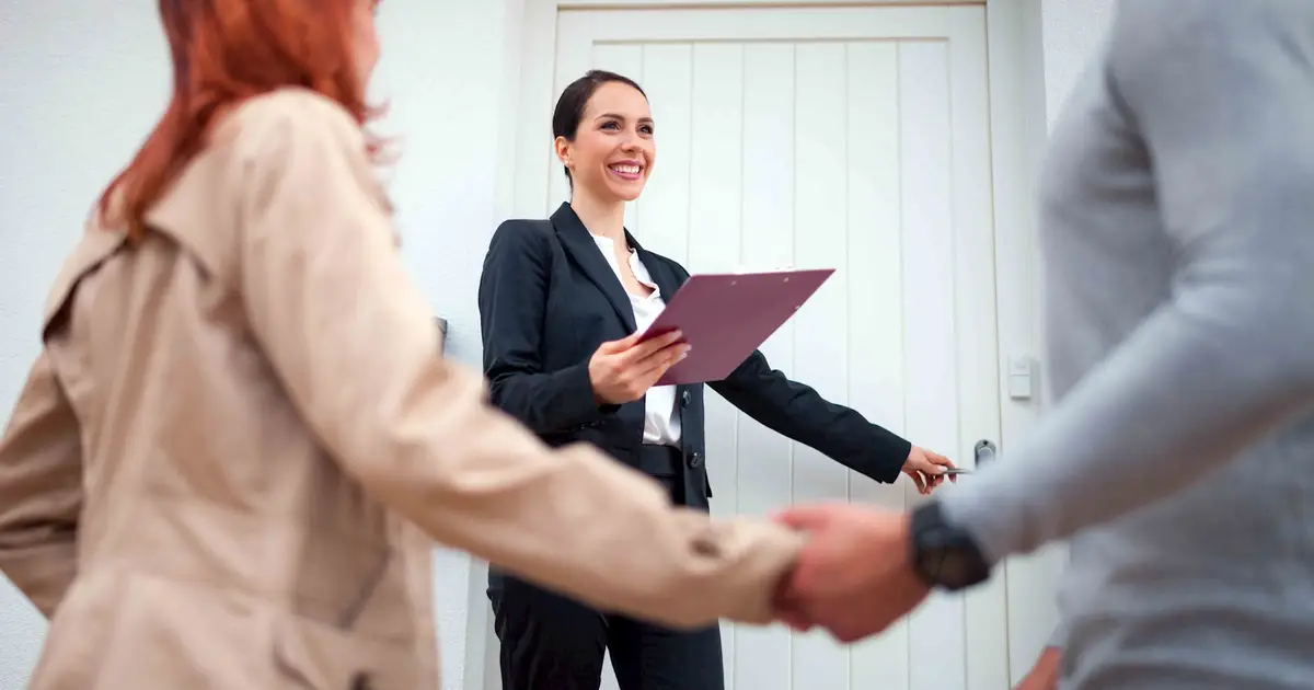 Real estate agent welcoming couple for home tour.