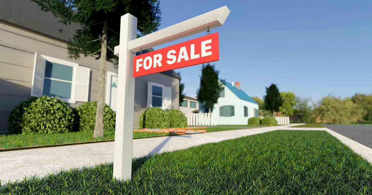 "For Sale" sign in front of suburban home.