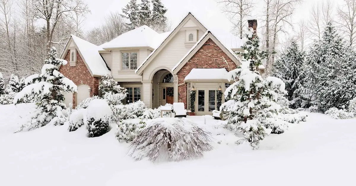 Snow-covered home surrounded by trees, showcasing a peaceful winter scene.
