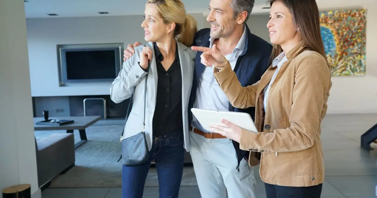 Real estate agent showing a modern home to a smiling couple.