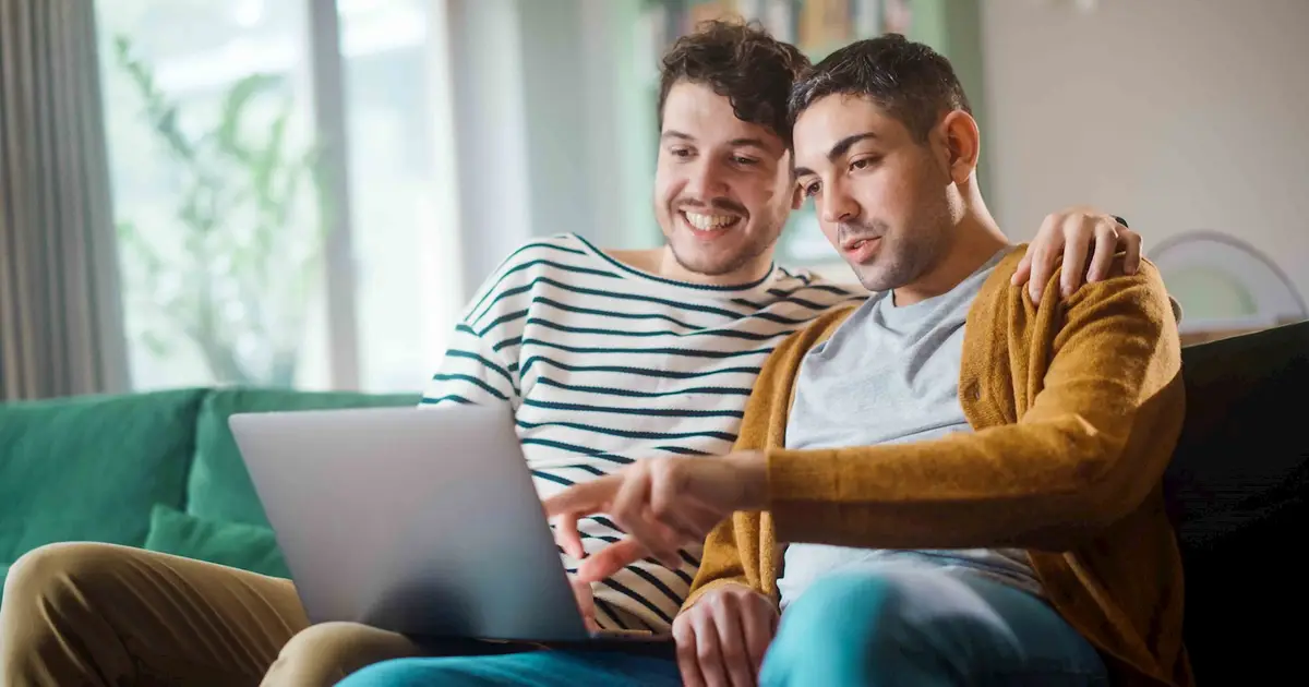 Smiling couple on couch looking at laptop.
