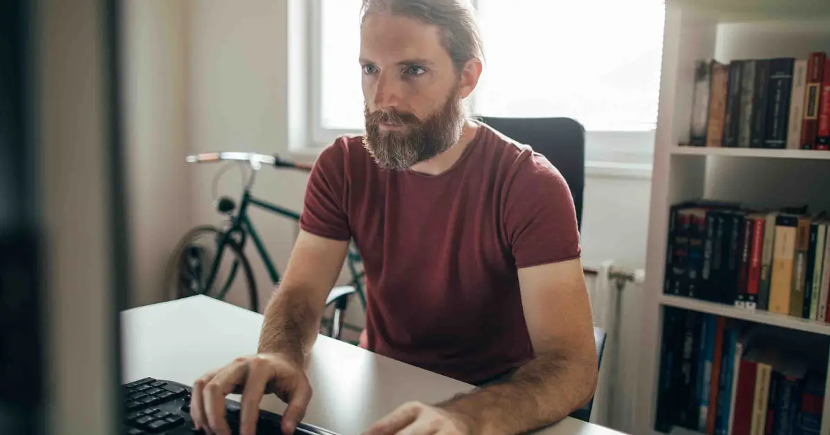Man working on computer in home office.