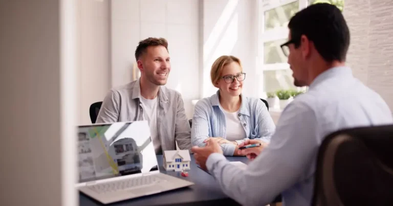 Smiling couple meets with loan officer in bright office setting.