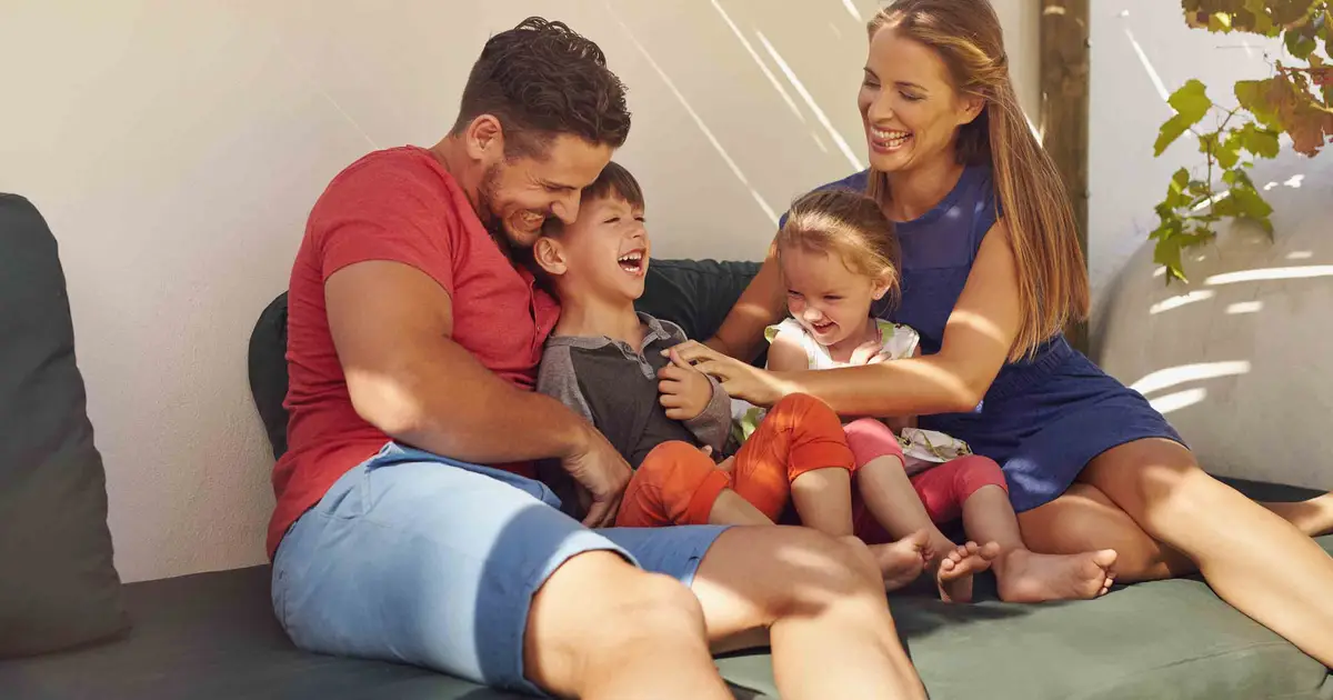 Family of four laughing together outside.