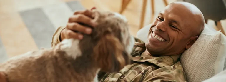 A soldier laying on the couch with his dog.