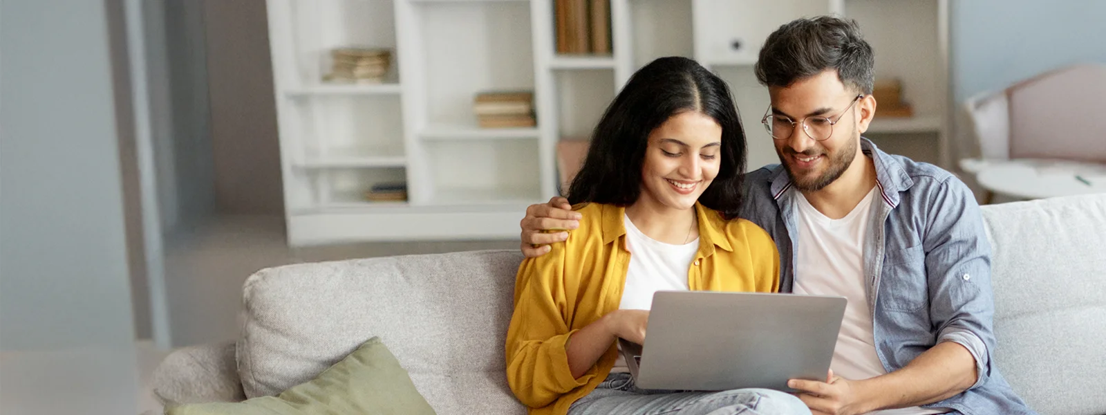 Couple sitting together on their couch using a laptop.