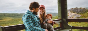 Father and mother with infant baby sitting on house porch.