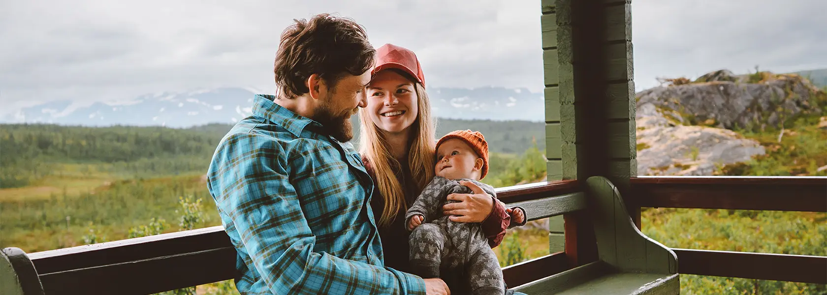 Father and mother with infant baby sitting on house porch.