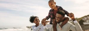 Parents carrying son on shoulders while at the beach.