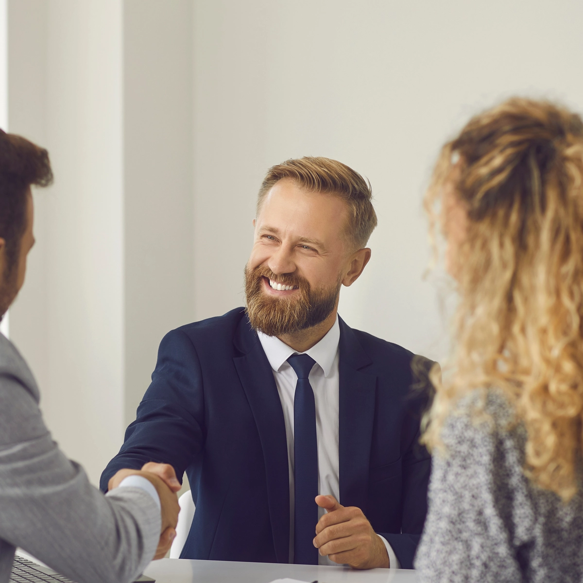 Man shaking hands with couple to close a home sale.