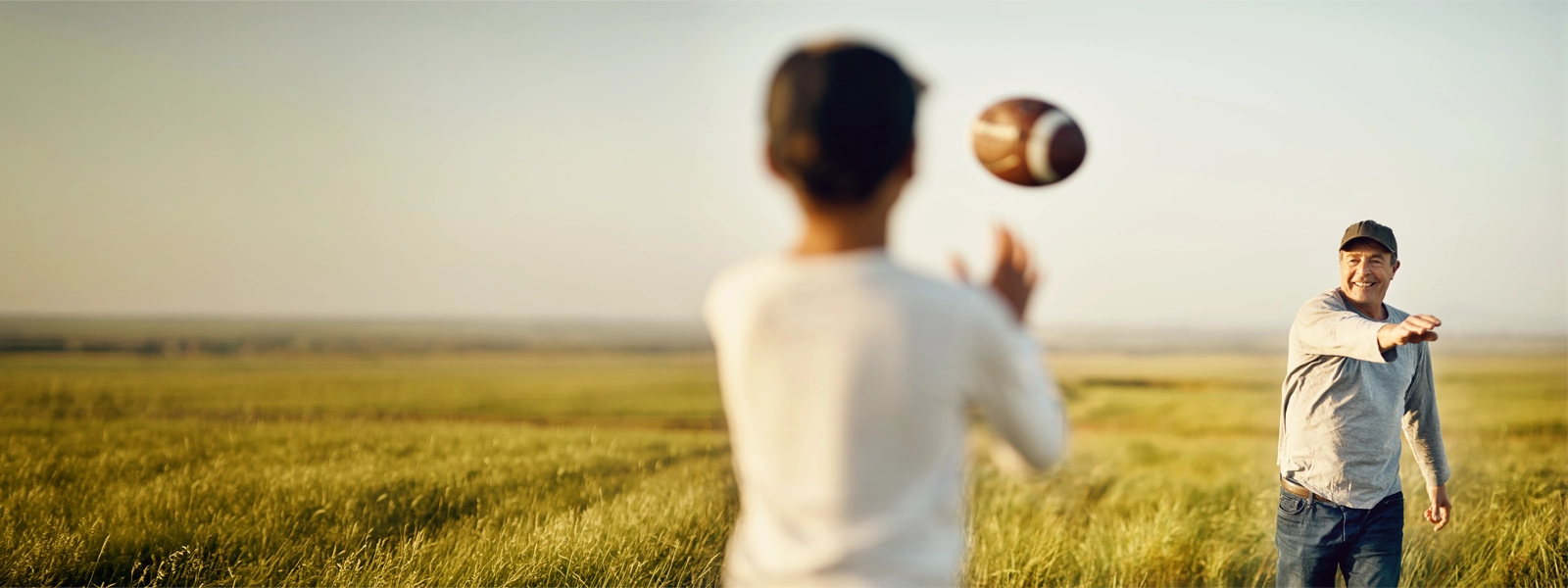 Father and son throwing a football on an open field.