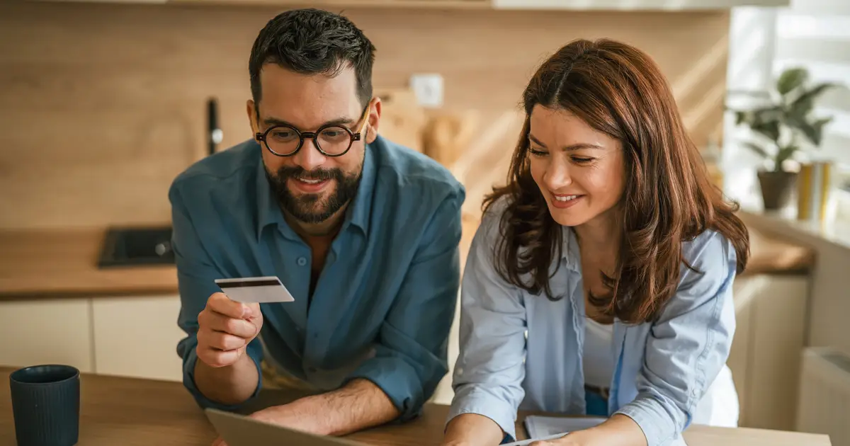 Couple smiling at credit card and laptop